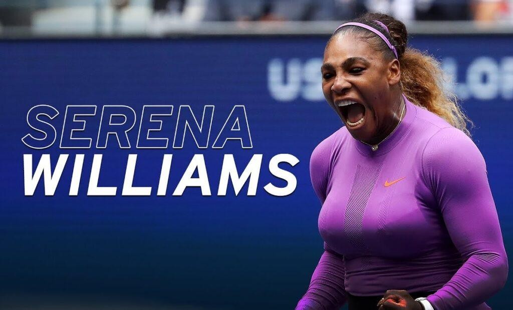 Serena Williams na korcie tenisowym, w tle stadion turnieju Wielkiego Szlema, trzymająca rakietę z pewnym wyrazem twarzy.