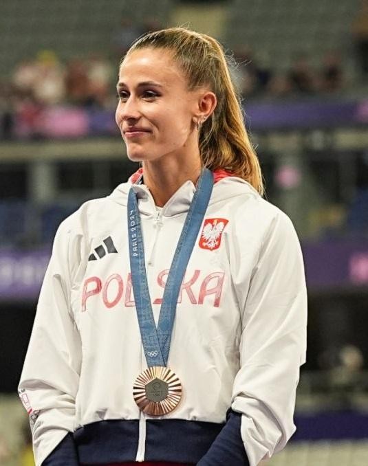 Natalia Bukowiecka w stroju sportowym, trzymająca dyplom, symbolizująca połączenie kariery sportowej z edukacją.