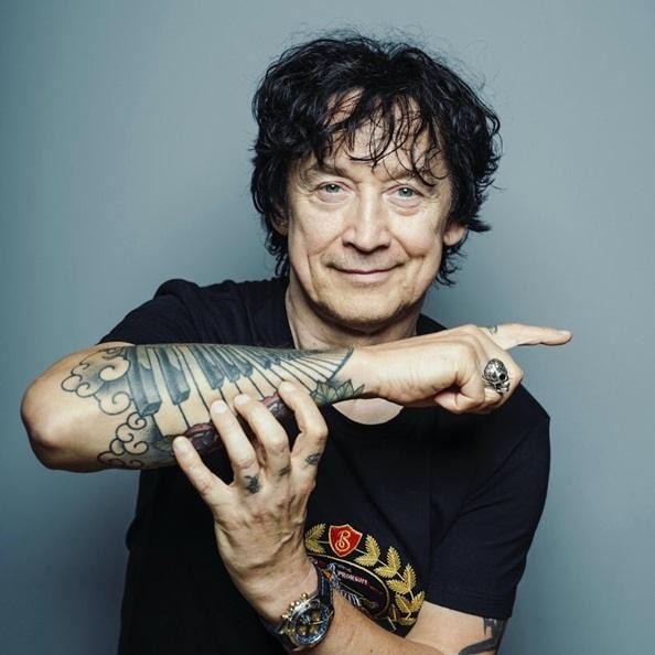 Jan Borysewicz, polski muzyk rockowy, uśmiechnięty i patrzący w obiektyw.