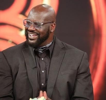 Shaquille O'Neal w akcji na boisku do koszykówki, w koszulce Los Angeles Lakers (nr 34), demonstrujący swoją dominację i siłę fizyczną podczas meczu NBA.