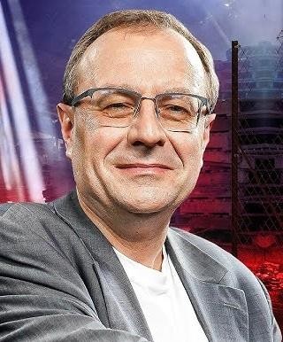 Antoni Dudek podczas wykładu lub wystąpienia medialnego, z ekspresją i gestykulacją.