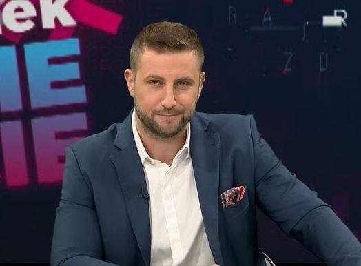Pusta scenografia studia telewizyjnego z biurkiem i krzesłami, gotowa na rozpoczęcie programu informacyjnego.