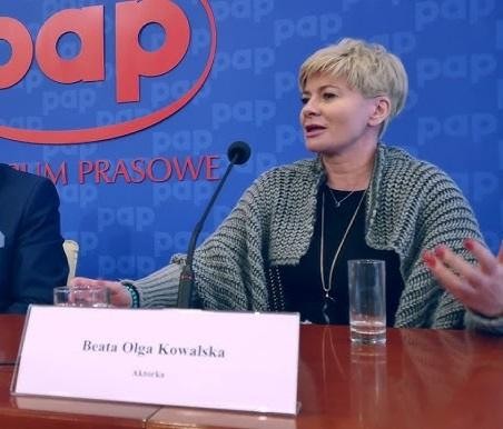 Beata Olga Kowalska w naturalnej pozie, ukazująca chwilę refleksji lub odpoczynku za kulisami, z subtelnym oświetleniem podkreślającym jej autentyczność.