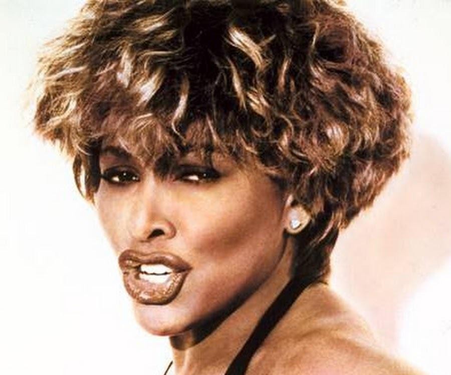 Tina Turner śpiewająca na koncercie, w zbliżeniu, z widoczną pasją i emocjami podczas występu.